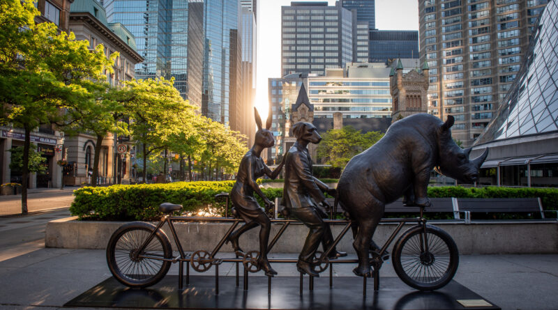 Today in the early hours of the morning, a new bronze sculpture pedalled into David Pecaut Square in Toronto's Entertainment District. He Was On A Ride to a Safer Place, by world-renowned artists Gillie and Marc, invites passersby to hop on the fourth seat and take a whimsical ride while delivering messages of equality, acceptance, and conservation. The sculpture will be on display for one year and was brought to the city by the Toronto Downtown West BIA. (CNW Group/Toronto Downtown West BIA)